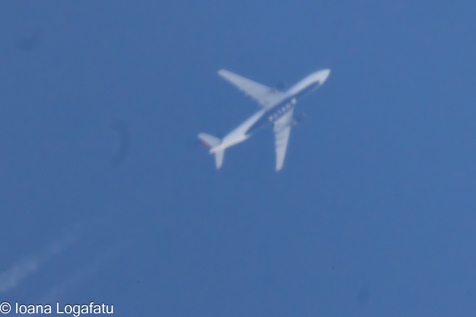 High above the clouds, a jet traces its flight
